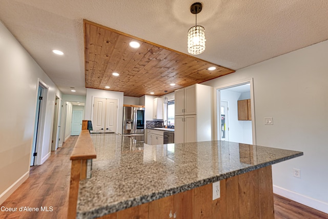 kitchen with stainless steel appliances, baseboards, wood finished floors, recessed lighting, and dark stone countertops