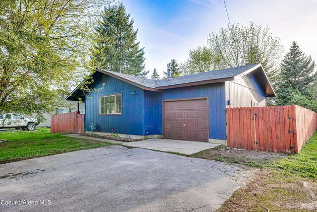 view of front of house with an attached garage, fence, asphalt driveway, and a shingled roof
