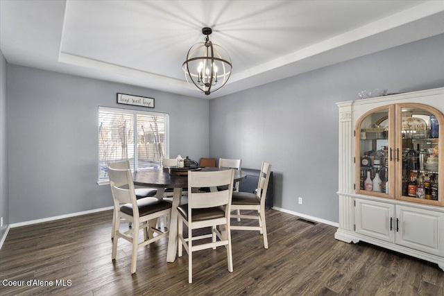 8747 Salmonberry Lp, Hayden, ID 83835 - dining space featuring a raised ceiling, a chandelier, dark wood finished floors, and baseboards