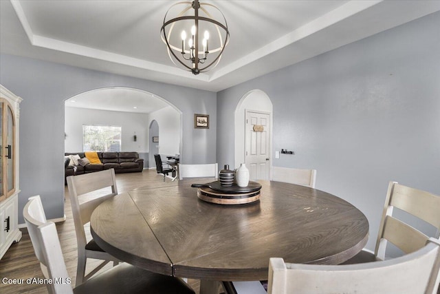 8747 Salmonberry Lp, Hayden, ID 83835 - dining space featuring arched walkways, a chandelier, a tray ceiling, and dark wood-style floors