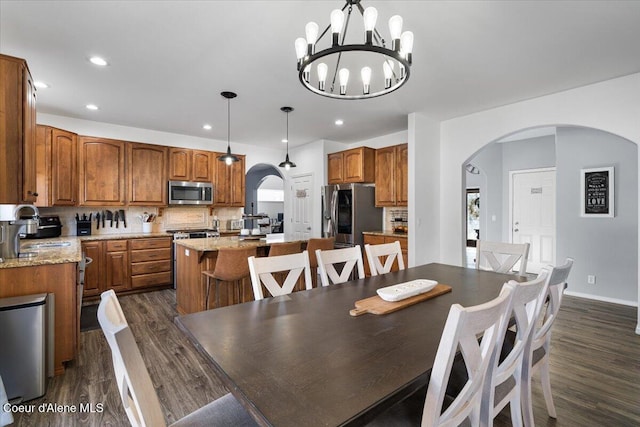 8747 Salmonberry Lp, Hayden, ID 83835 - dining area with arched walkways, dark wood-style flooring, recessed lighting, a chandelier, and baseboards