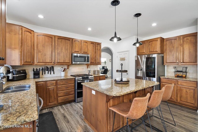 8747 Salmonberry Lp, Hayden, ID 83835 - kitchen with appliances with stainless steel finishes, a sink, arched walkways, a center island, and decorative backsplash