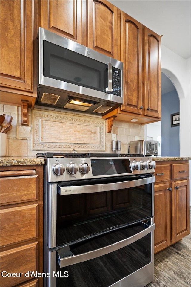 8747 Salmonberry Lp, Hayden, ID 83835 - kitchen with stainless steel appliances, brown cabinetry, and decorative backsplash