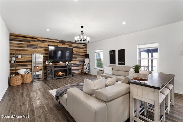 8747 Salmonberry Lp, Hayden, ID 83835 - living area with wooden walls, an accent wall, dark wood finished floors, a lit fireplace, and a chandelier