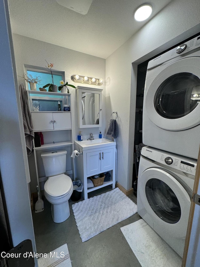 1203 Chestnut St, Sandpoint, ID 83864 - bathroom featuring stacked washing machine and dryer, finished concrete flooring, vanity, and toilet