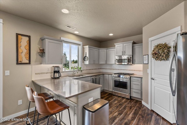 3402 N Croghan Dr, Post Falls, ID 83854 - kitchen with appliances with stainless steel finishes, a sink, a peninsula, tasteful backsplash, and a textured ceiling