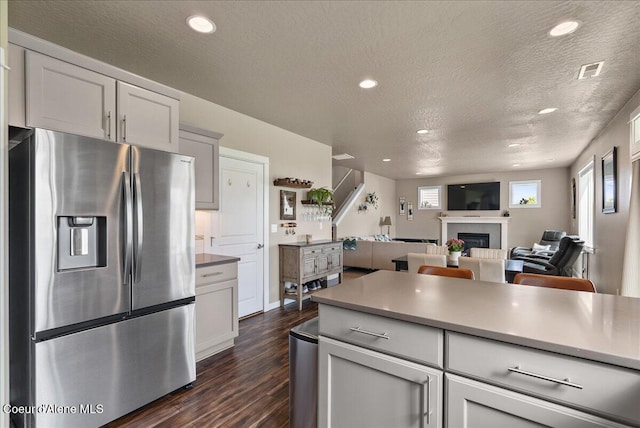 3402 N Croghan Dr, Post Falls, ID 83854 - kitchen featuring stainless steel refrigerator with ice dispenser, dark wood finished floors, a textured ceiling, a glass covered fireplace, and open floor plan