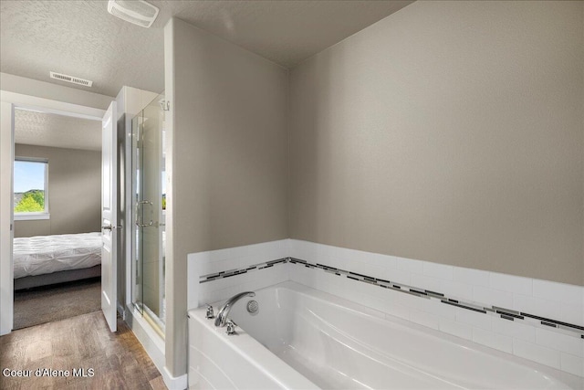 3402 N Croghan Dr, Post Falls, ID 83854 - ensuite bathroom featuring a bath, wood finished floors, a stall shower, and a textured ceiling