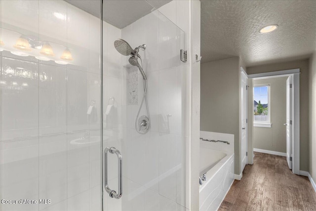 3402 N Croghan Dr, Post Falls, ID 83854 - bathroom featuring a stall shower, a bath, a textured ceiling, wood finished floors, and baseboards