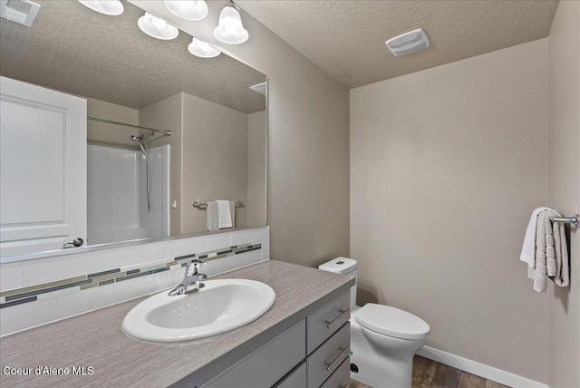 3402 N Croghan Dr, Post Falls, ID 83854 - bathroom featuring wood finished floors, vanity, toilet, tasteful backsplash, and a textured ceiling