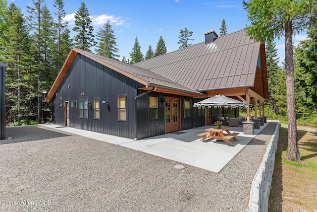 rear view of property featuring french doors, a patio area, and metal roof