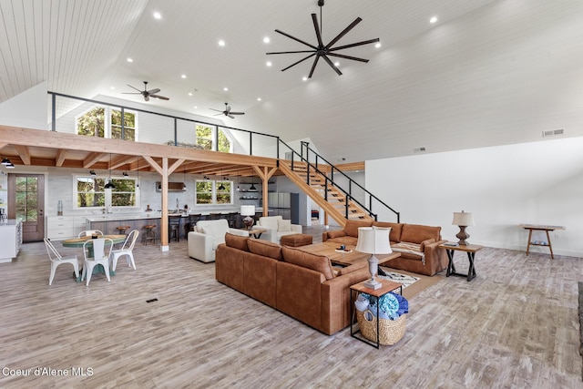living area featuring recessed lighting, wood finished floors, stairs, ceiling fan, and a high ceiling