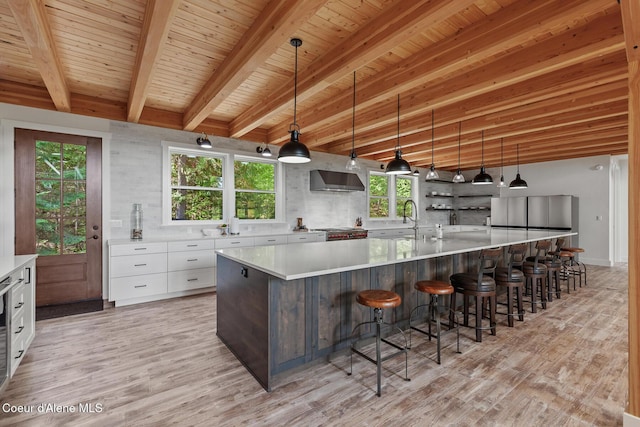kitchen featuring light wood-type flooring, white cabinetry, light countertops, healthy amount of natural light, and beam ceiling