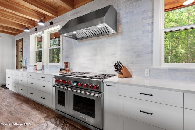 kitchen with range with two ovens, wall chimney range hood, beam ceiling, wood ceiling, and tasteful backsplash