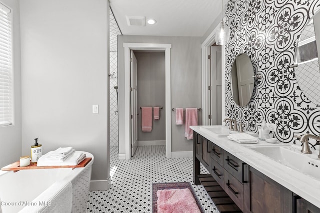 bathroom with baseboards, a bath, and double vanity