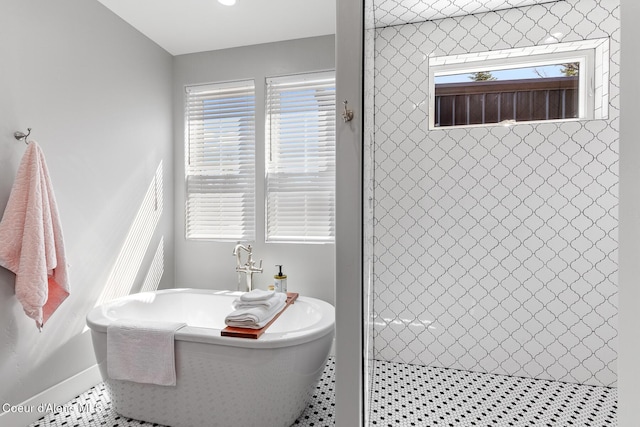 bathroom with plenty of natural light, tiled shower, a soaking tub, and baseboards