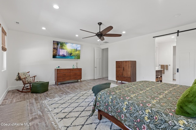 bedroom featuring a barn door, wood finished floors, recessed lighting, baseboards, and ceiling fan