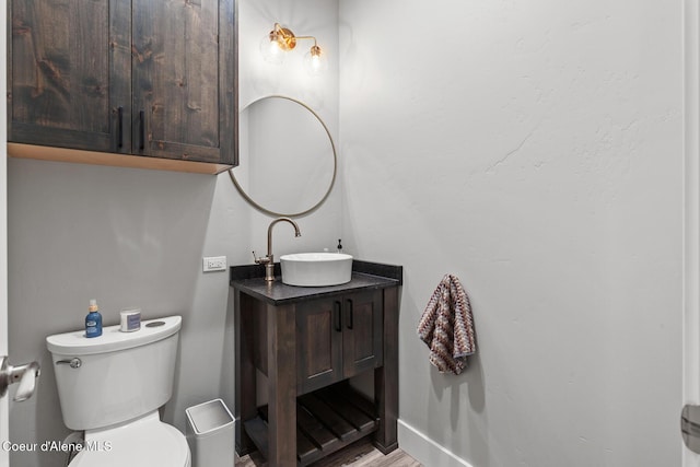 bathroom with wood finished floors, toilet, vanity, and baseboards