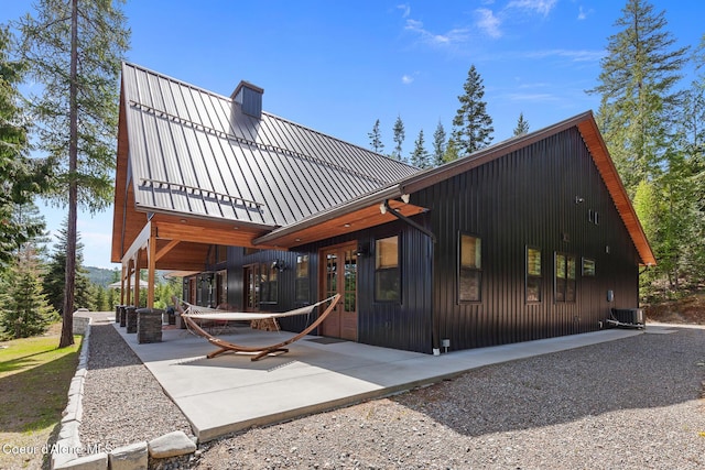 back of property featuring central air condition unit, a standing seam roof, and metal roof