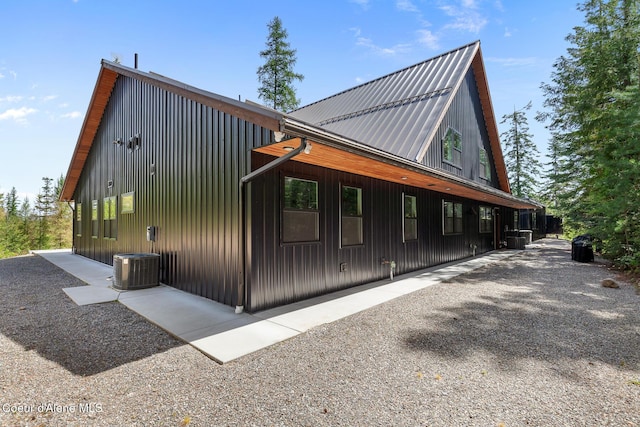 view of side of home featuring central air condition unit and metal roof