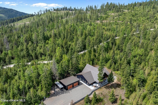 aerial view of property and surrounding area with a forest and a mountain backdrop