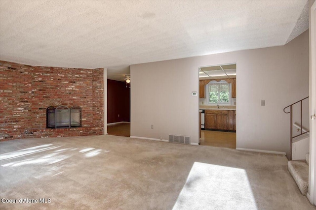 unfurnished living room featuring stairs, a fireplace, carpet floors, baseboards, and a textured ceiling