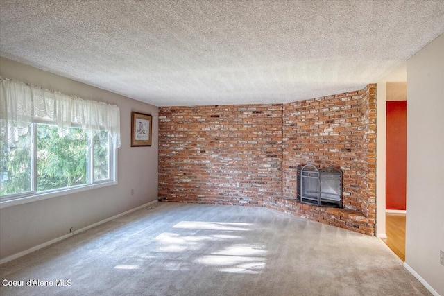 unfurnished living room with baseboards, a textured ceiling, carpet flooring, brick wall, and a brick fireplace