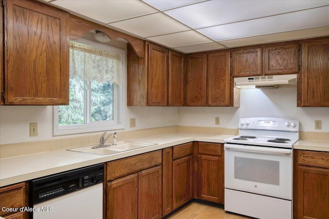 kitchen featuring white appliances, a sink, under cabinet range hood, and brown cabinets