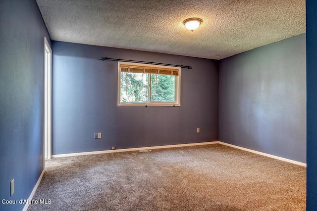 spare room featuring carpet floors, a textured ceiling, and baseboards