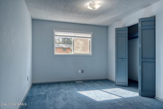 unfurnished bedroom with carpet floors, a textured ceiling, a closet, and baseboards