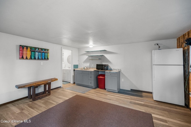8072 W Radmer Rd, Rathdrum, ID 83858 - kitchen featuring freestanding refrigerator, gray cabinetry, light wood-style flooring, baseboards, and light countertops