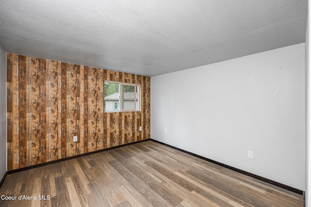 8072 W Radmer Rd, Rathdrum, ID 83858 - spare room with wood finished floors, baseboards, wood walls, and a textured ceiling