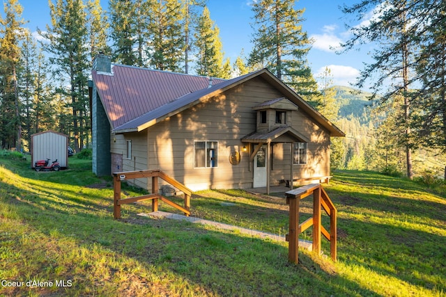 8072 W Radmer Rd, Rathdrum, ID 83858 - back of house with a chimney, a yard, a storage unit, and metal roof