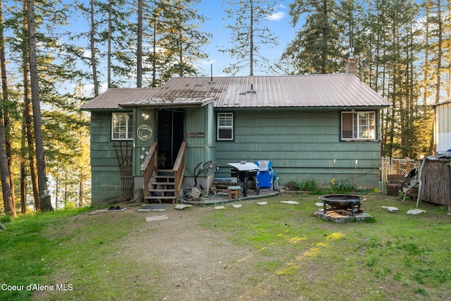 8072 W Radmer Rd, Rathdrum, ID 83858 - rear view of house featuring a fire pit, metal roof, a chimney, and a lawn