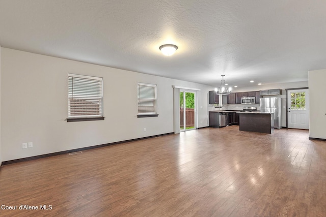1201 E Locust Ave, Coeur Dalene, ID 83814 - unfurnished living room with a chandelier, dark wood finished floors, healthy amount of natural light, baseboards, and recessed lighting