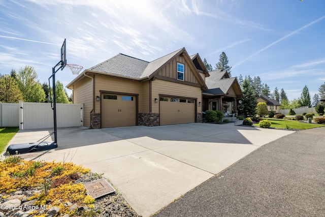 view of front of house featuring a gate, board and batten siding, driveway, fence, and stone siding
