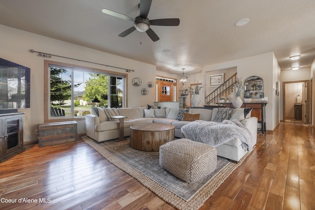 living area with stairs, hardwood / wood-style flooring, and ceiling fan