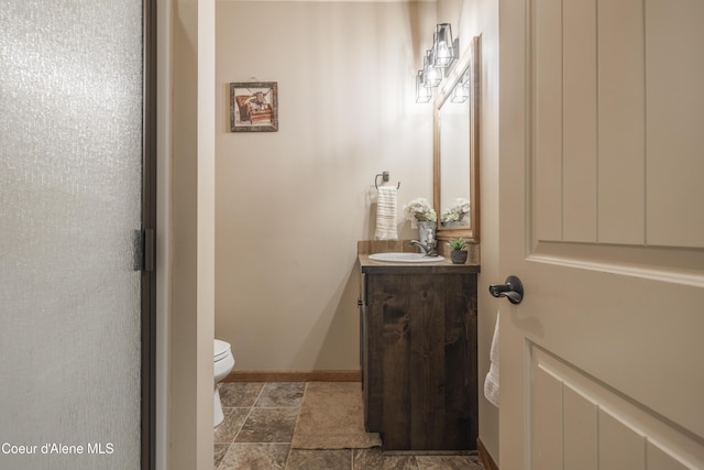 bathroom with vanity, toilet, and stone finish flooring