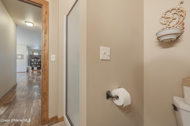 bathroom with hardwood / wood-style flooring, baseboards, and toilet