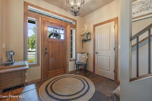 foyer entrance with a chandelier and baseboards