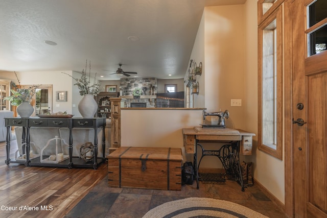 foyer featuring ceiling fan, a stone fireplace, and wood finished floors