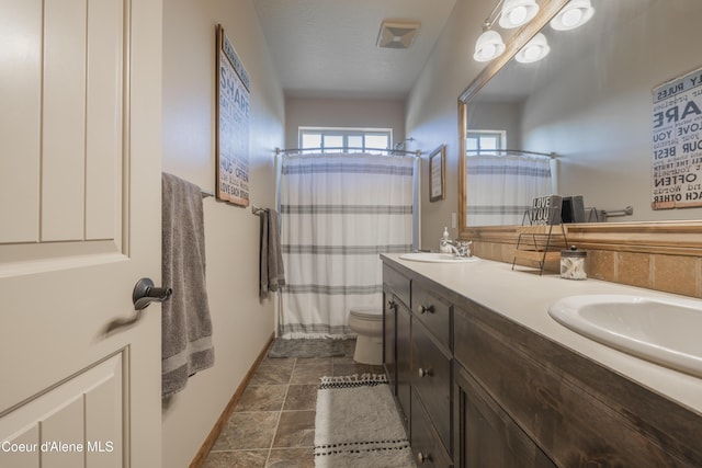 bathroom with baseboards, toilet, double vanity, and a shower with shower curtain
