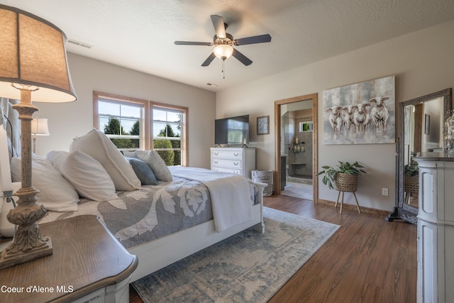 bedroom featuring wood finished floors, baseboards, a ceiling fan, and ensuite bath