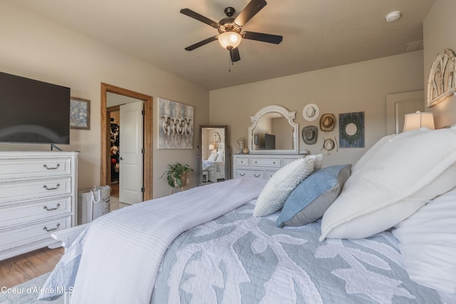 bedroom with a spacious closet, a ceiling fan, and wood finished floors