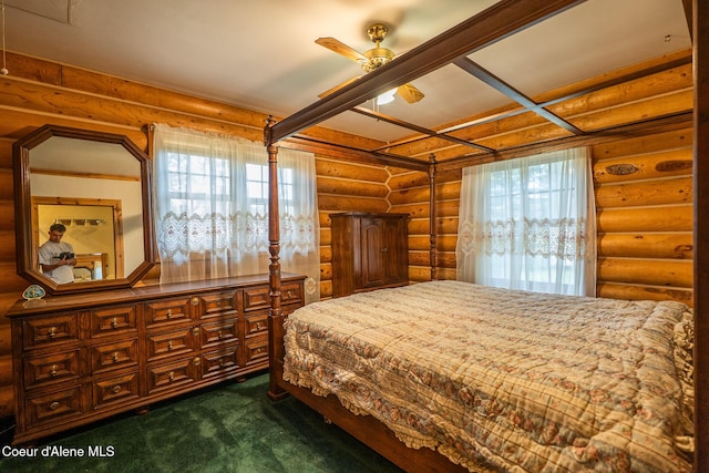 bedroom featuring log walls, multiple windows, and dark colored carpet