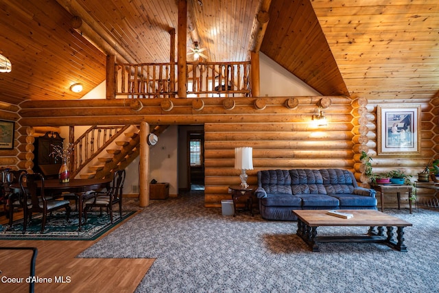 living area with rustic walls, wooden ceiling, stairway, ceiling fan, and high vaulted ceiling
