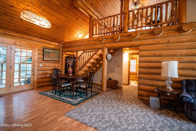 dining area with stairway, rustic walls, wood ceiling, high vaulted ceiling, and wood finished floors