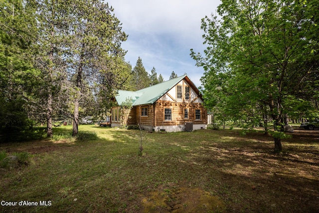 view of property exterior with log siding, central air condition unit, a yard, and metal roof