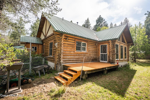 back of house featuring log exterior, a wooden deck, and metal roof
