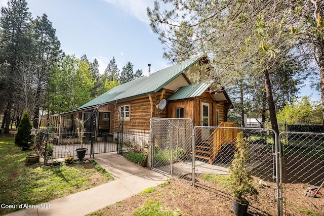 view of home's exterior featuring a gate, metal roof, fence, and log exterior